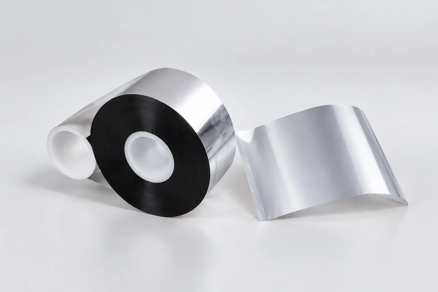 Close-up of a black TTO ribbon roll beside a curved flexible packaging film sample.